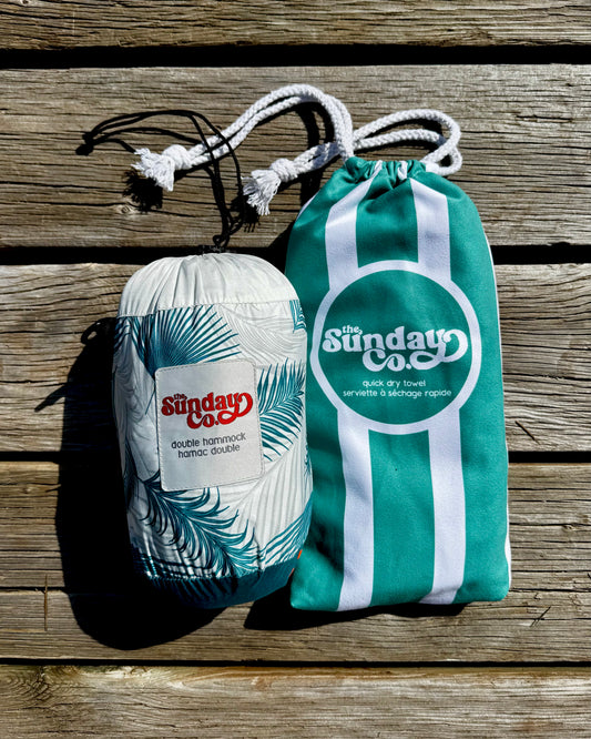 The Sunday Company Green Palms Hammock and East Coast Green Towel, both packed in their matching travel pouches.