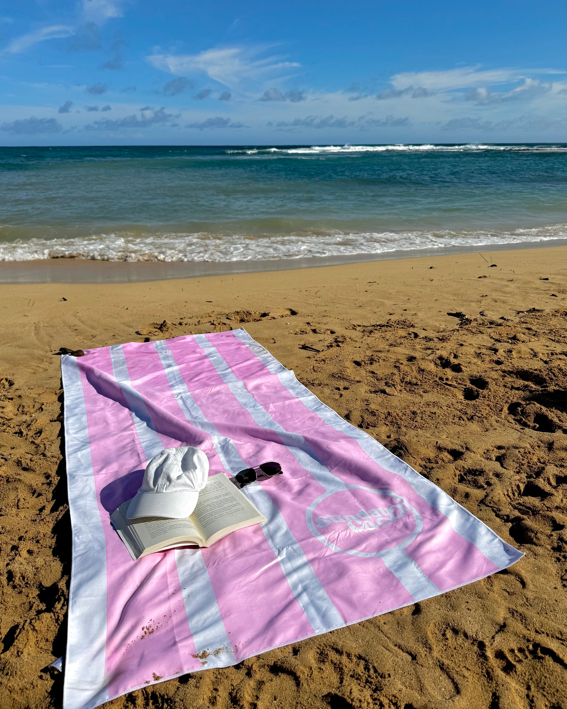 Pink towel on a sandy beach with ocean waves in the background